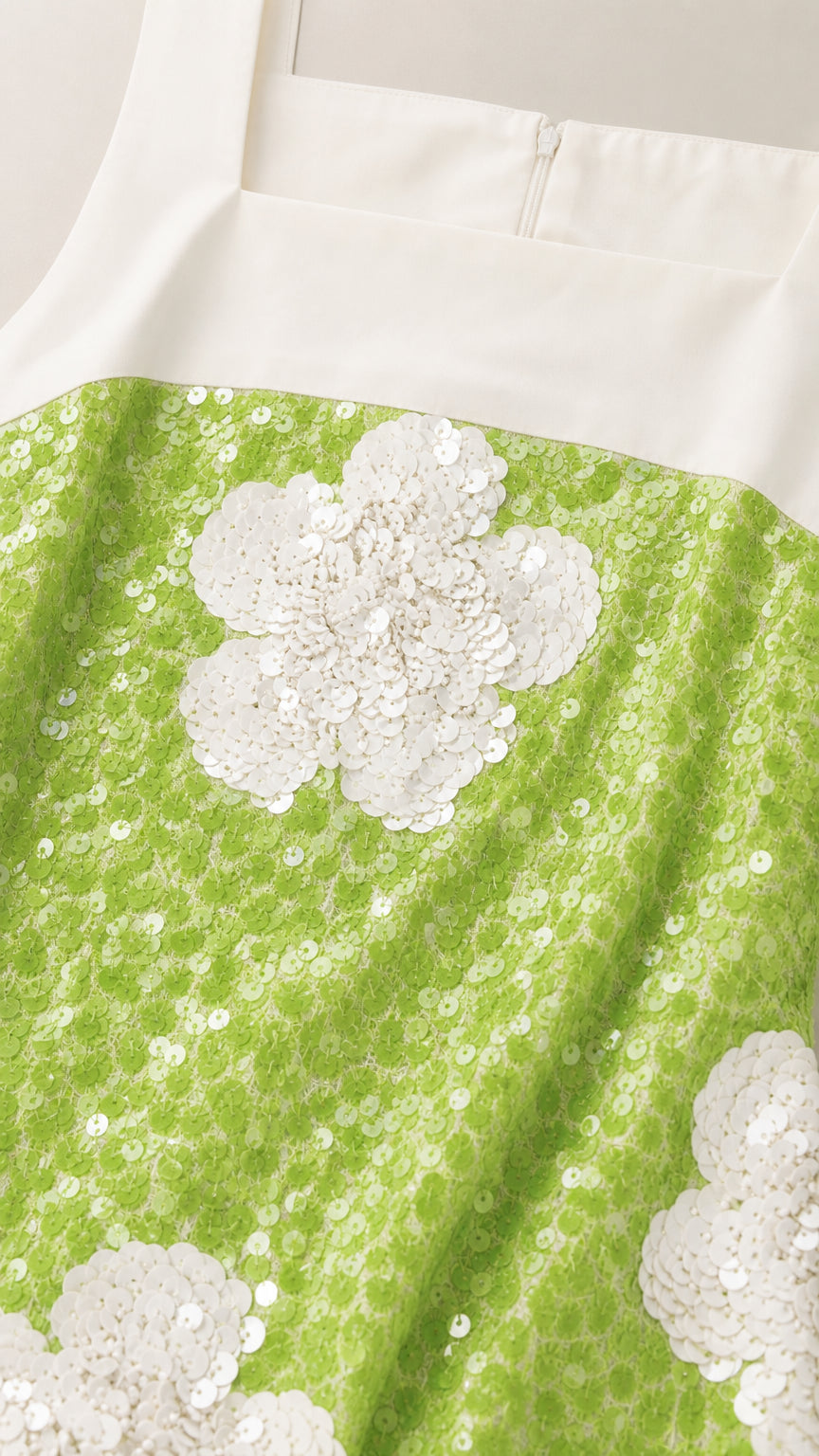 Close-up detail of lime green and white floral sequin embroidery with zipper closure