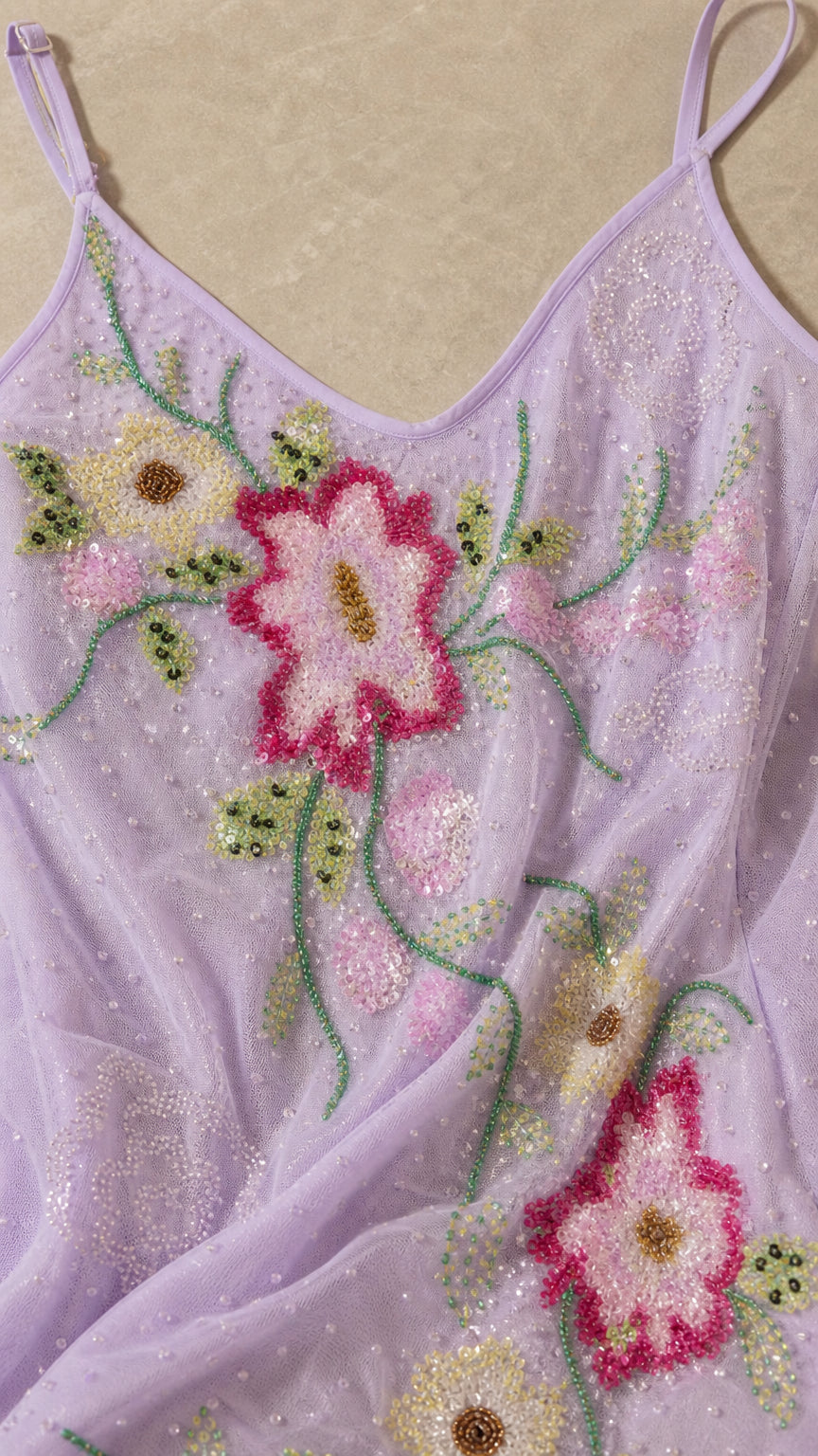 Close-up of intricate pink and green floral beadwork on lavender fabric