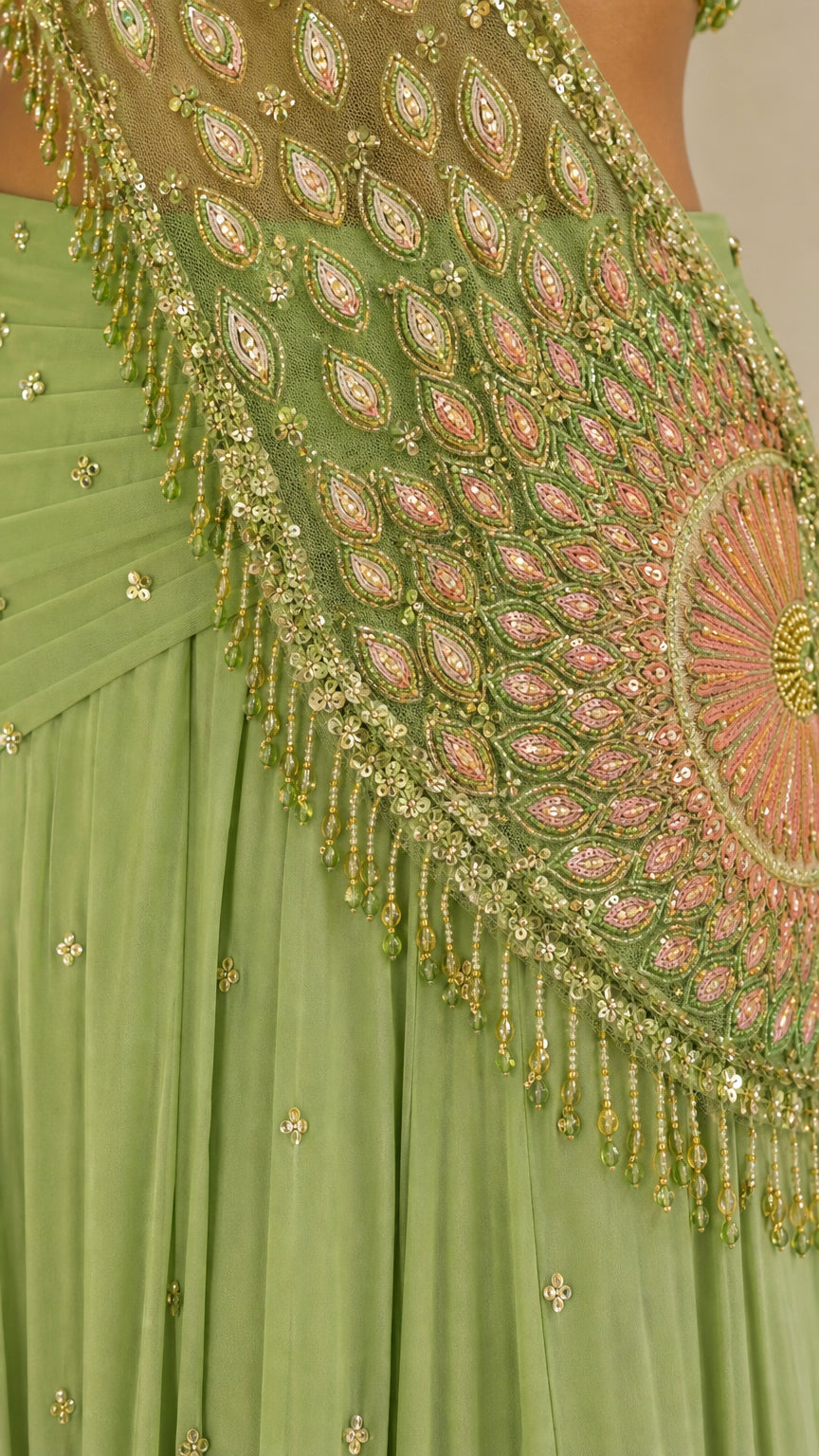 Close-up detail of intricate beadwork, sequins, and hanging fringe on green drape