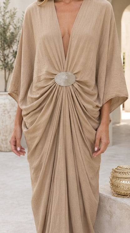 Close-up of deep plunge neckline and metallic buckle center gathering on beige maxi dress