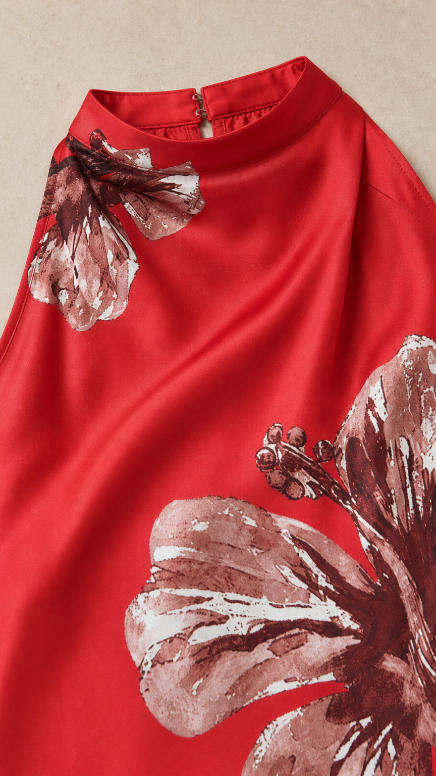Close-up detail of smooth red satin fabric with printed flower and high mock collar