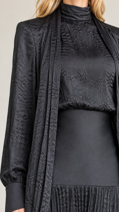 Close-up detail of black mock neck, textured fabric, wide waistband, and draped cardigan