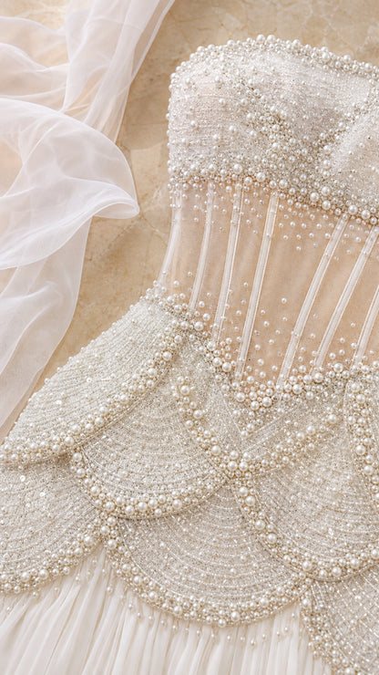 Close-up detail of sheer mesh corset bodice with boning and layered pearl scalloped beadwork