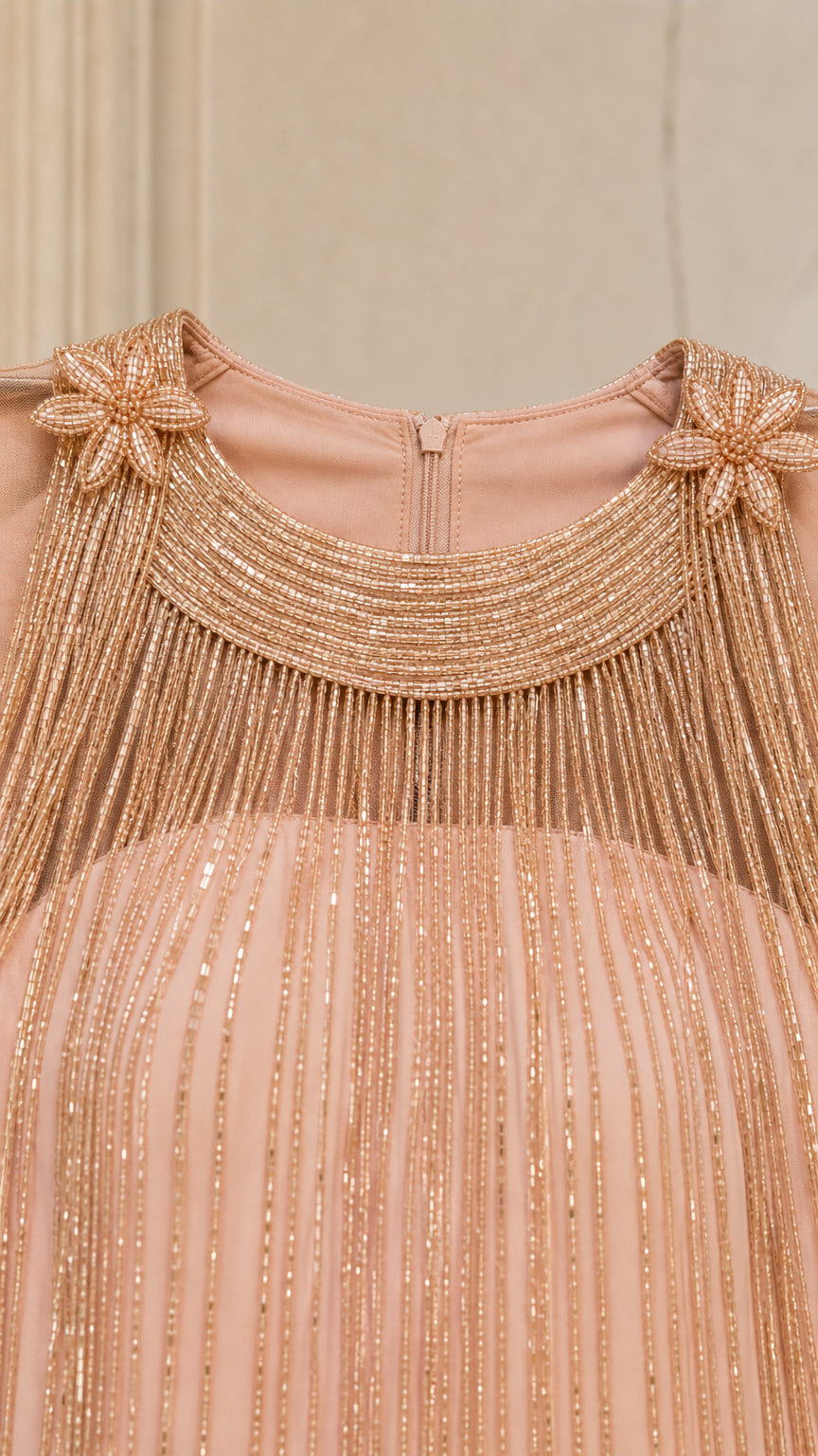 Close-up detail of neckline, beaded fringe, and floral shoulder appliques