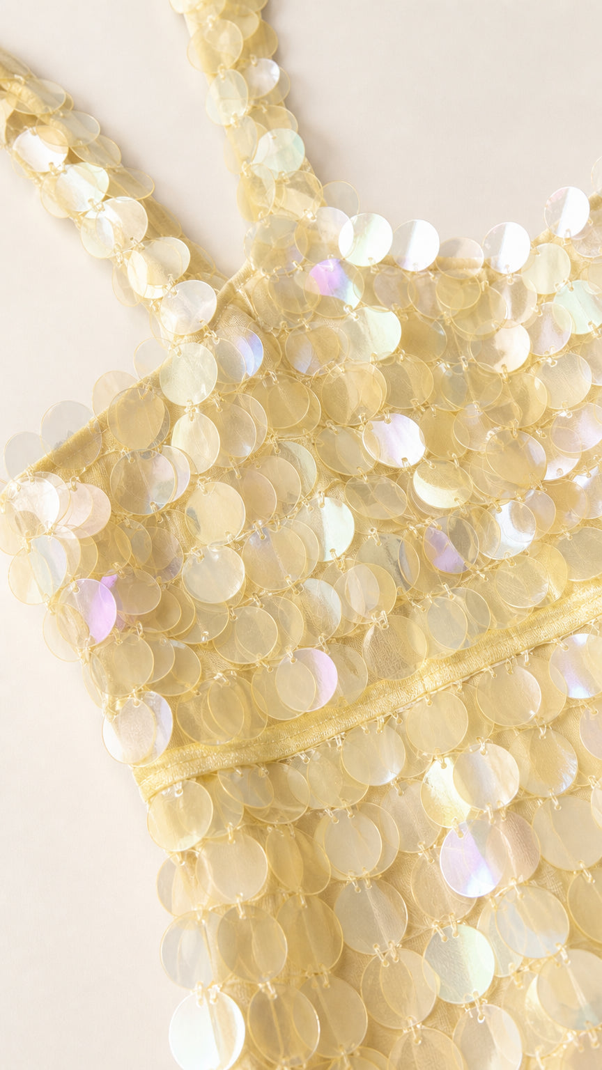 Close-up detail of pale yellow iridescent circular paillette sequins on bodice strap
