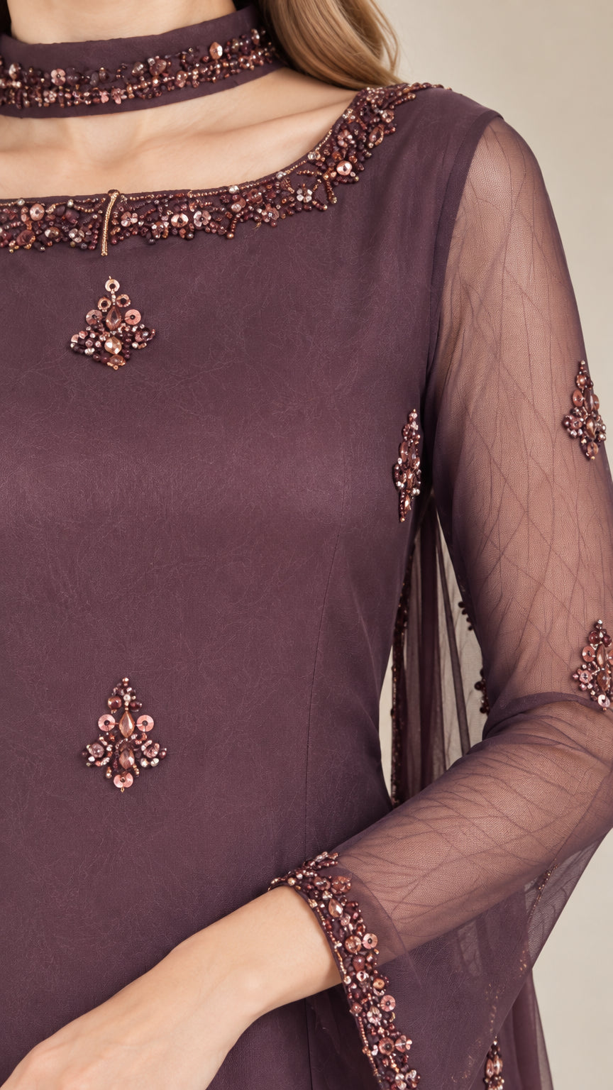 Close-up detail of beaded neckline and sheer sleeve cuff on plum tunic