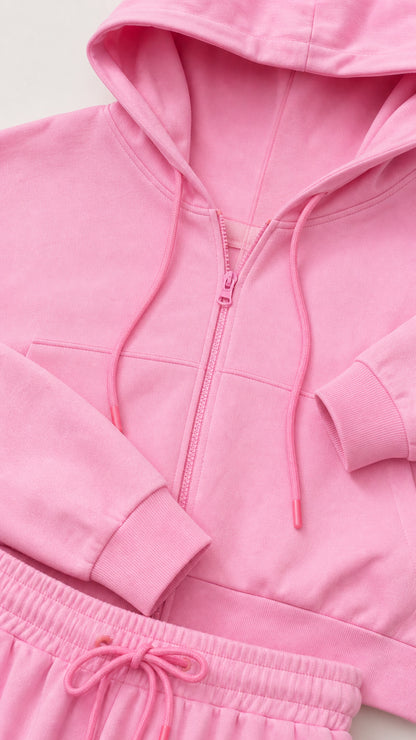 Close-up detail of pink cropped hoodie zipper, hood drawstrings, and waistband