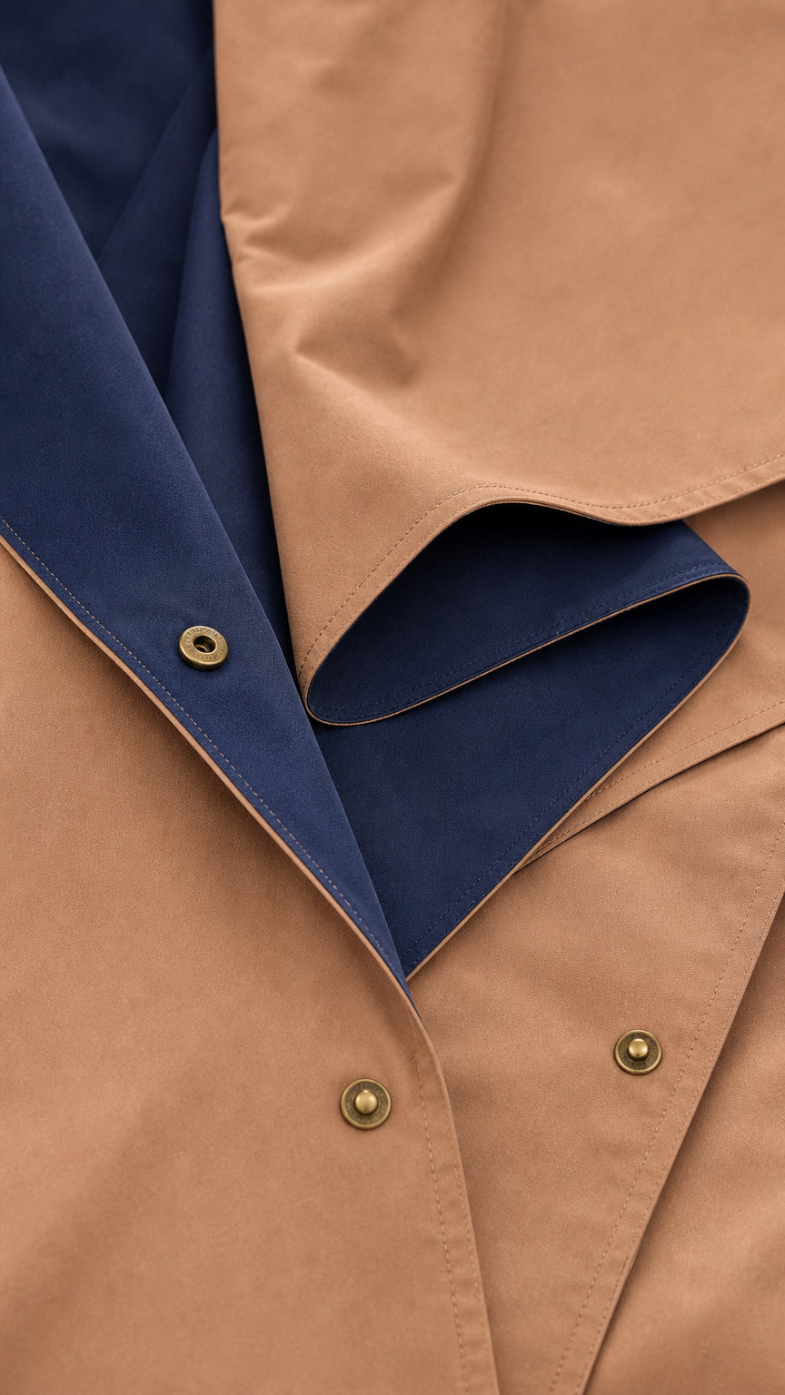 Close-up detail of smooth camel fabric texture, snap buttons, and navy inner lining