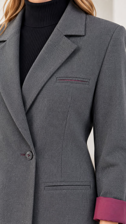 Close-up detail of charcoal grey blazer notched lapel, welt pocket, and contrast cuff