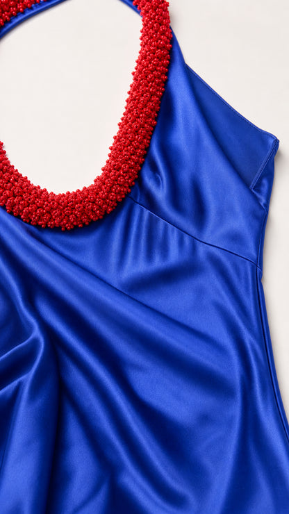 Close up detail of royal blue satin fabric and red beaded halter trim
