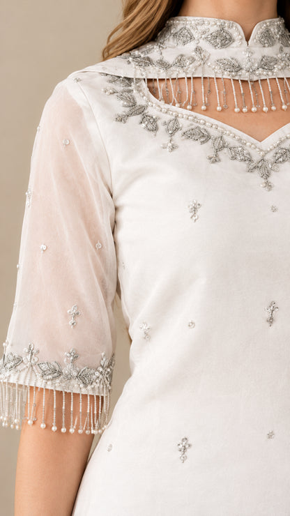 Close-up of beaded fringe hem and neckline embroidery on sheer white sleeve