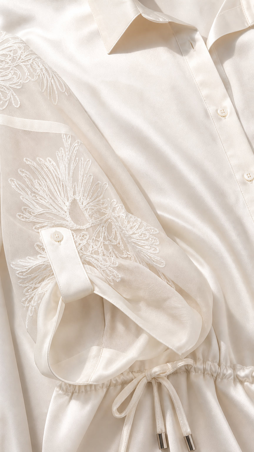 Close-up detail of embroidered sheer sleeve, button-down front, and drawstring waist