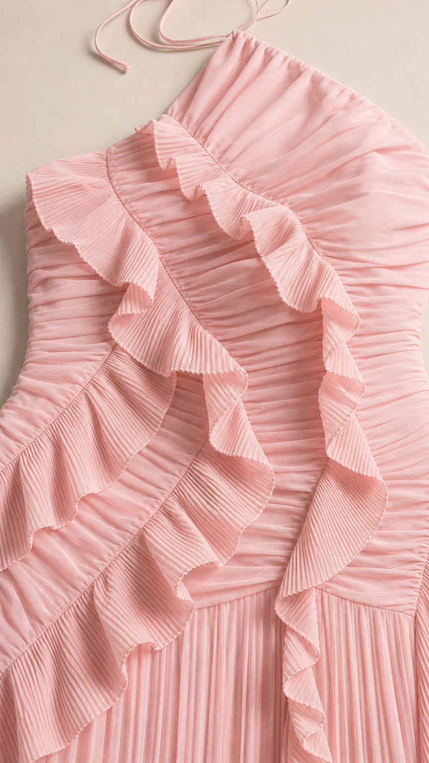 Close-up detail of blush pink pleated chiffon fabric with ruffle trim