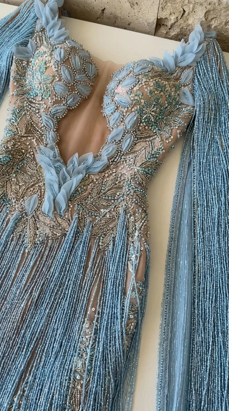 Close-up flat lay of light blue gown bodice with mesh illusion and petal beading