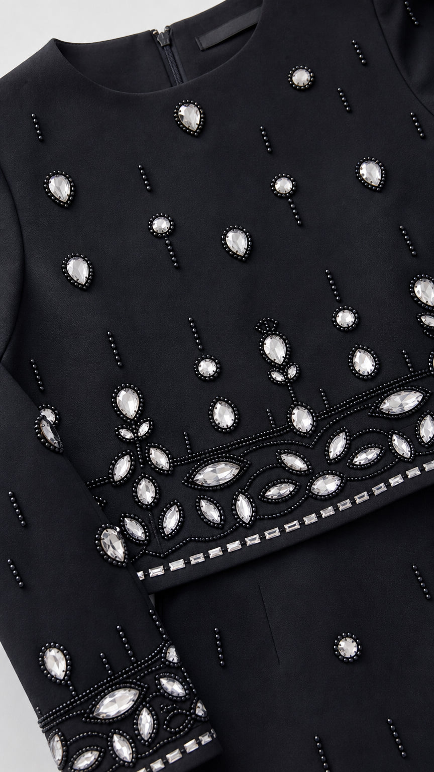 Close-up detail of sparkling crystal rhinestones and beadwork on neckline, hem, and sleeve cuff