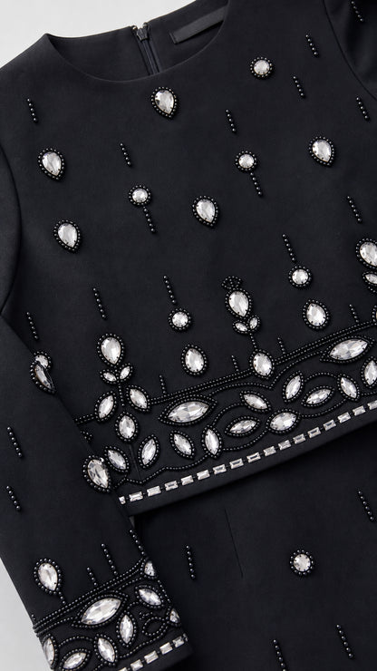 Close-up detail of sparkling crystal rhinestones and beadwork on neckline, hem, and sleeve cuff