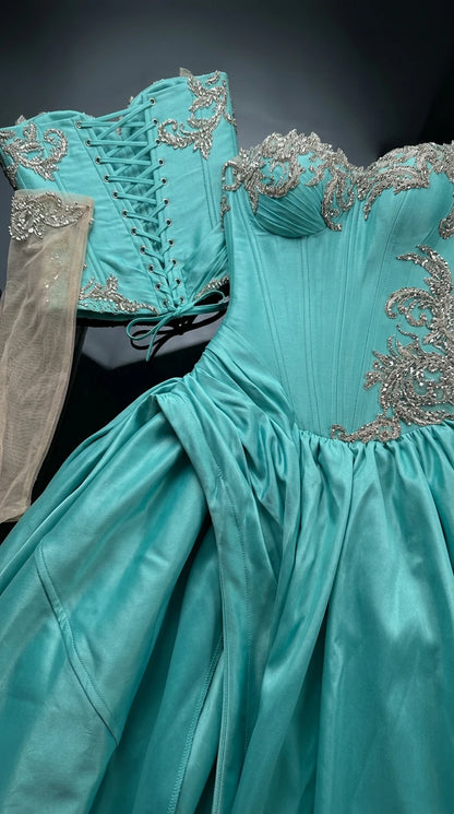 Flat lay detail of turquoise corset bodice, sheer embroidered arm cuffs, and lace-up back