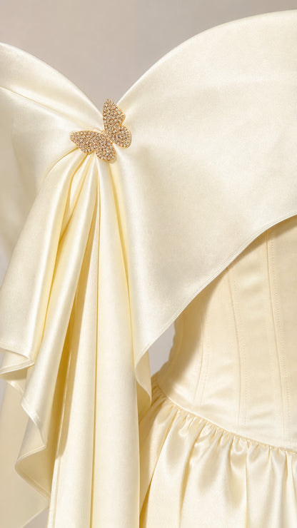 Close-up detail of off-the-shoulder neckline with satin fold and sparkling gold crystal butterfly brooch
