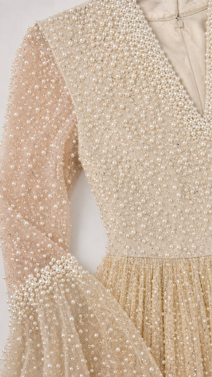 Close-up detail of pearl embellishments and bell sleeve cuff on champagne gown