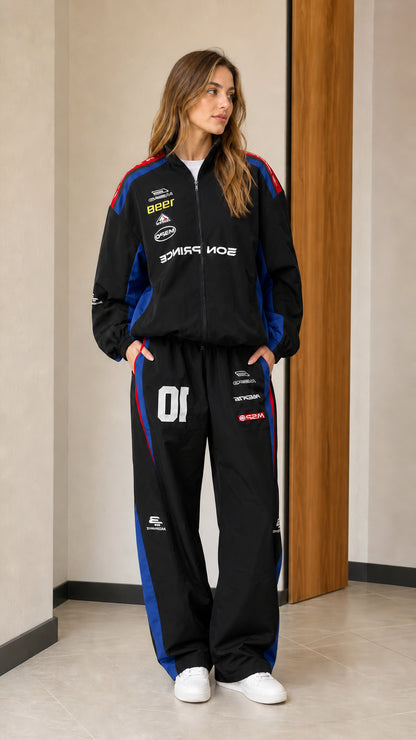 Front view of woman wearing black colorblock racing two-piece tracksuit set