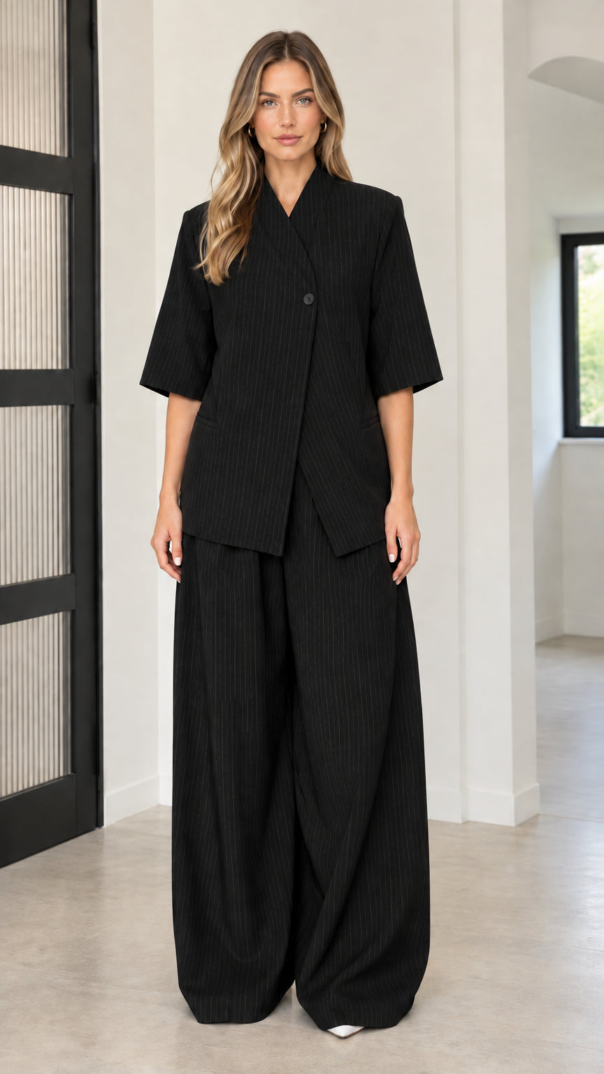 Front full-length view of model wearing Black asymmetric blazer and wide-leg pant set