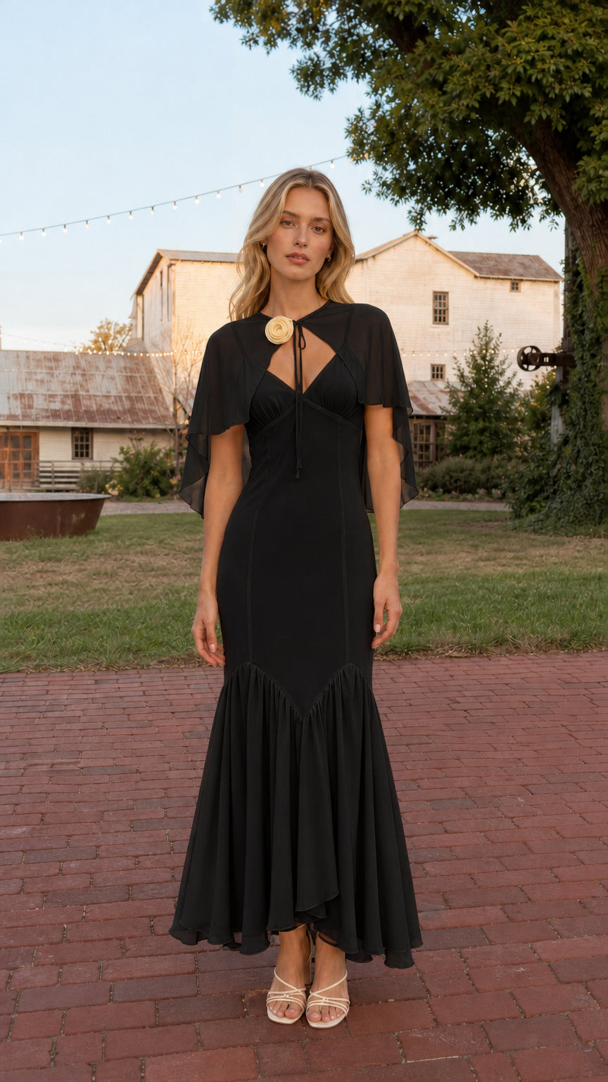 Front view of model wearing Black floral rosette capelet mermaid maxi dress
