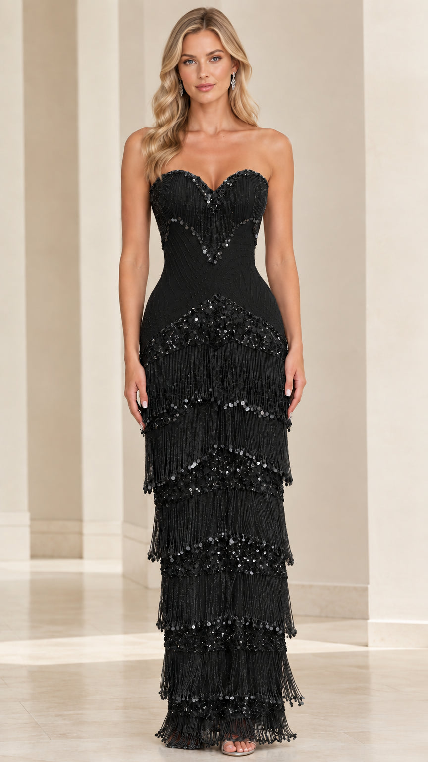 Front view of model wearing black strapless sweetheart tiered fringe maxi gown
