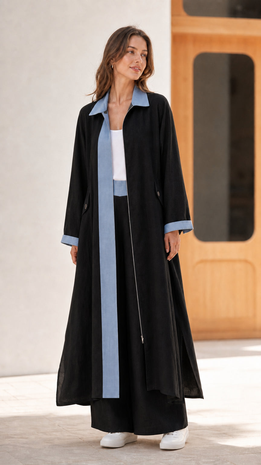 Full length view of black longline coat and matching wide-leg trousers set with blue trim