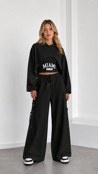 Model wearing black 3-piece crop hoodie and lace-up wide leg sweatpants set