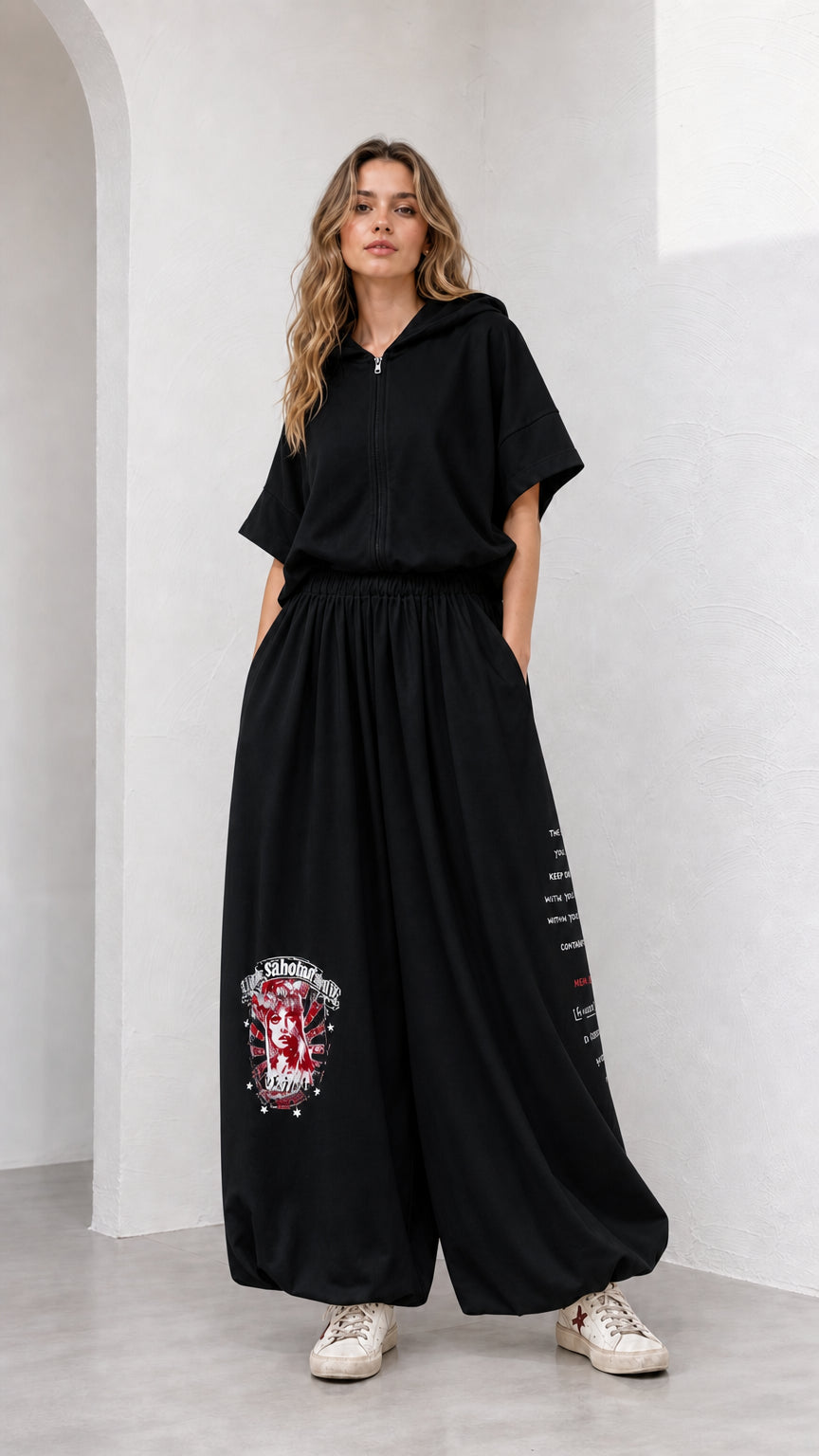 Model wearing black short-sleeve hooded top and matching balloon pants set