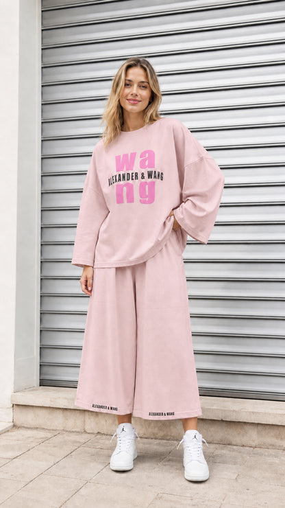 Model wearing dusty pink graphic pullover and wide-leg cropped bottoms set