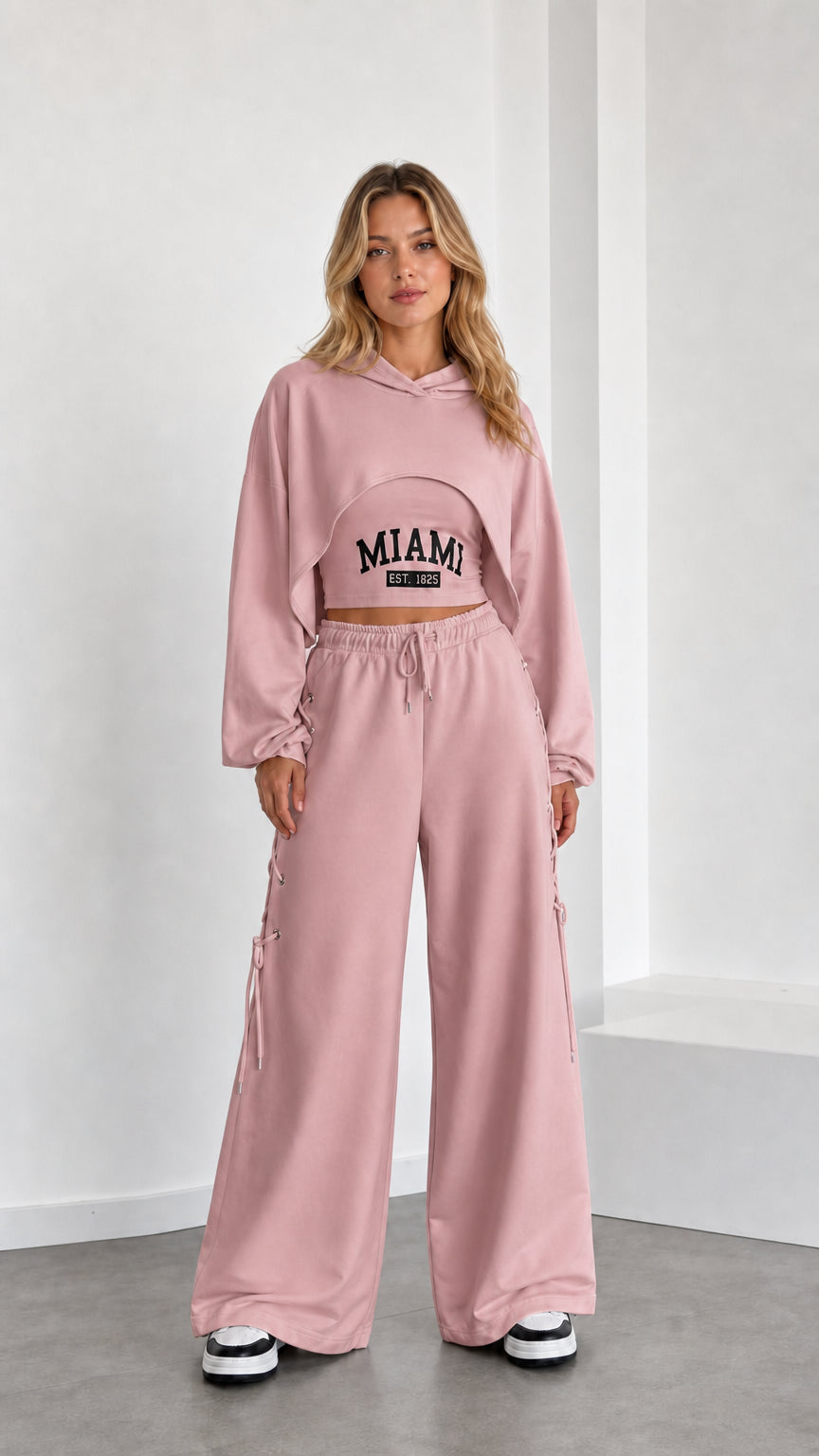 Model wearing pink 3-piece crop hoodie and wide leg track pants set
