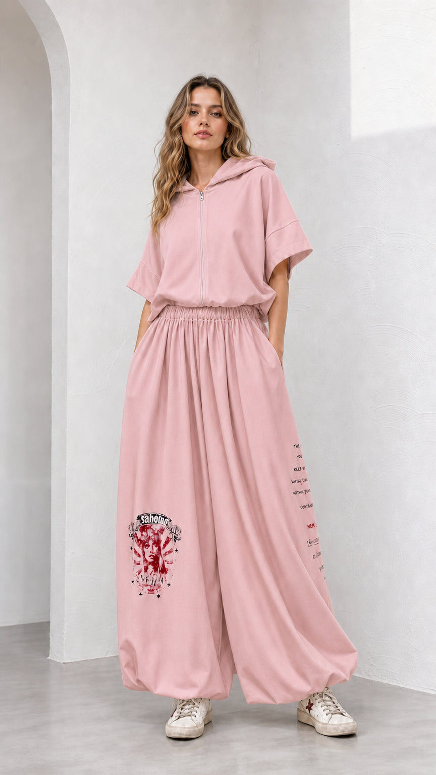 Model wearing dusty pink short-sleeve hooded top and wide-leg graphic pants set