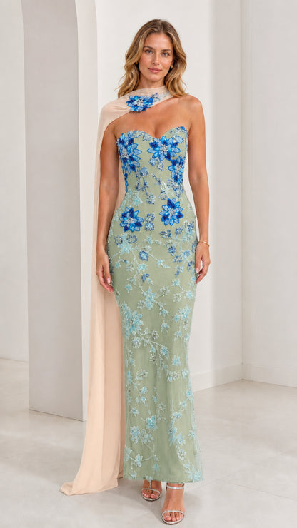 Model wearing sage green strapless evening gown with blue floral beadwork and chiffon cape
