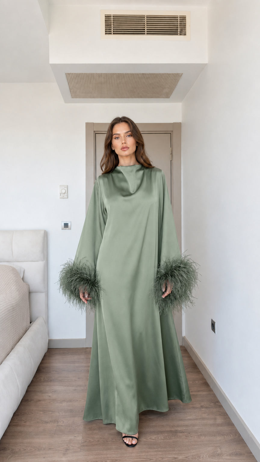Model wearing sage green satin maxi dress with feather cuffs