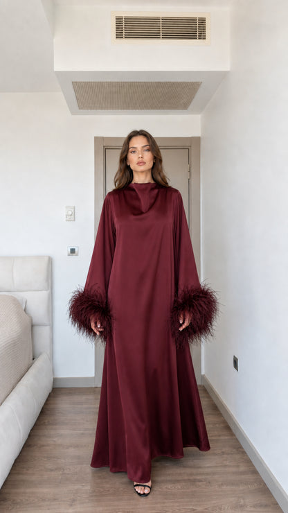 Model wearing rich burgundy wine red satin maxi dress with feather cuffs