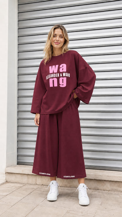 Model wearing burgundy graphic sweatshirt and wide-leg pants two piece set