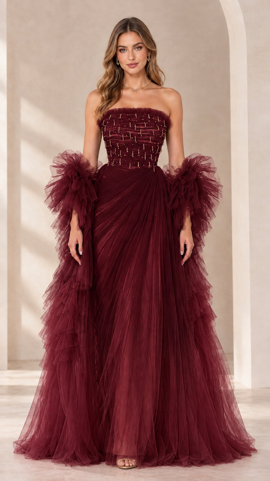 Full-length view of burgundy strapless beaded tulle evening gown with ruffled sleeve wraps