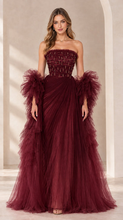 Full-length view of burgundy strapless beaded tulle evening gown with ruffled sleeve wraps
