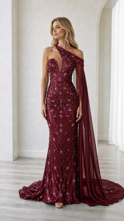 Front full-length view of the burgundy wine beaded one-shoulder formal gown with attached cape