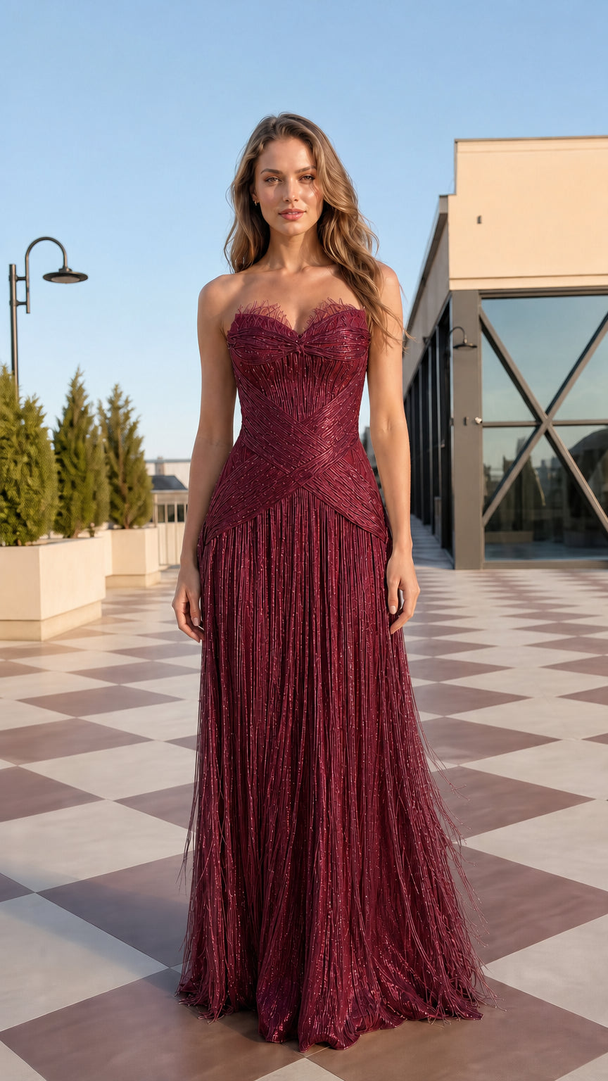 Front view of model wearing burgundy wine red strapless fringe maxi gown